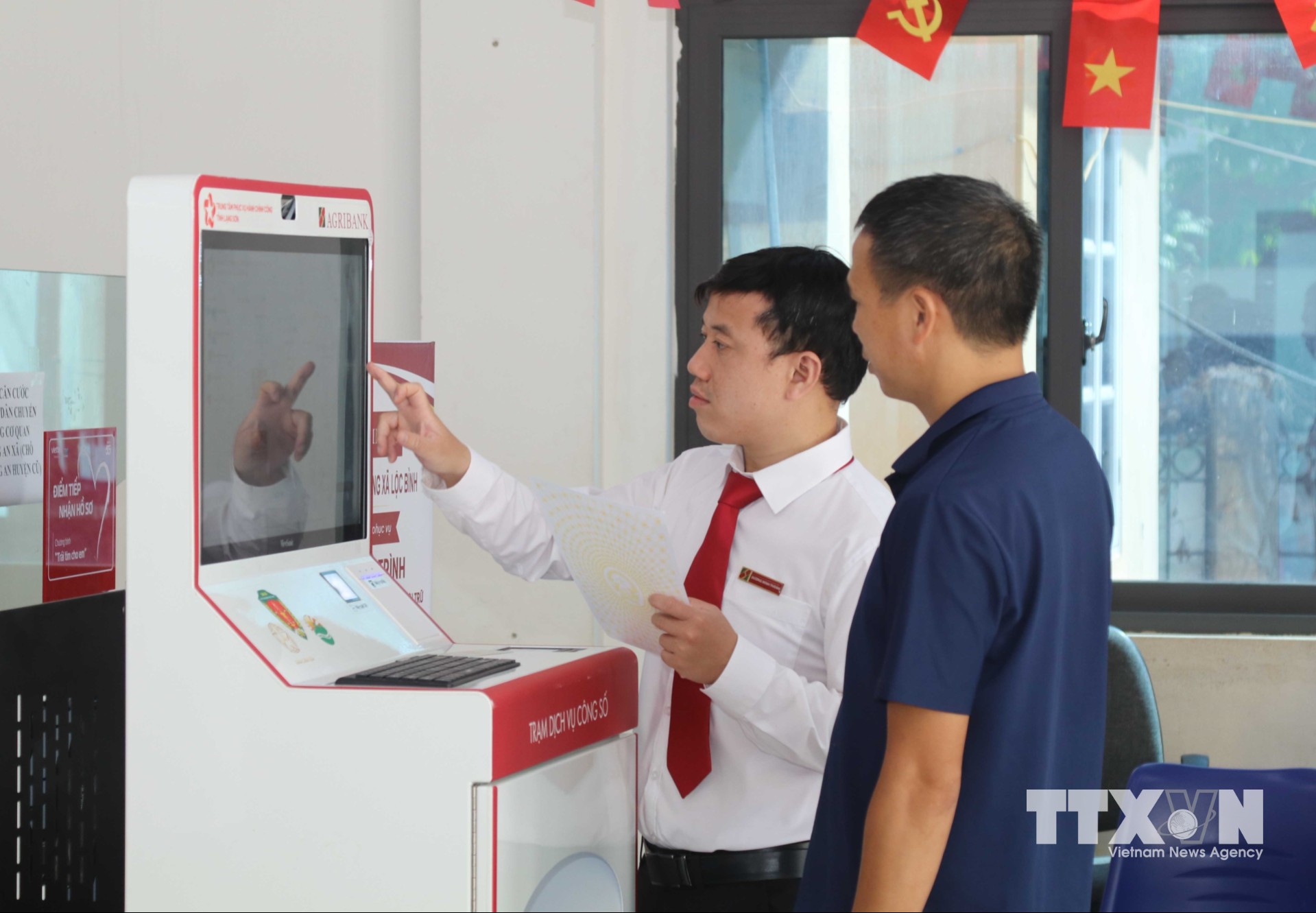 Cán bộ Agribank tỉnh Lạng Sơn hướng dẫn người dân thực hiện thủ tục hành chính qua “Trạm dịch vụ công số” xã Lộc Bình. (Ảnh: Quang Duy/TTXVN)
